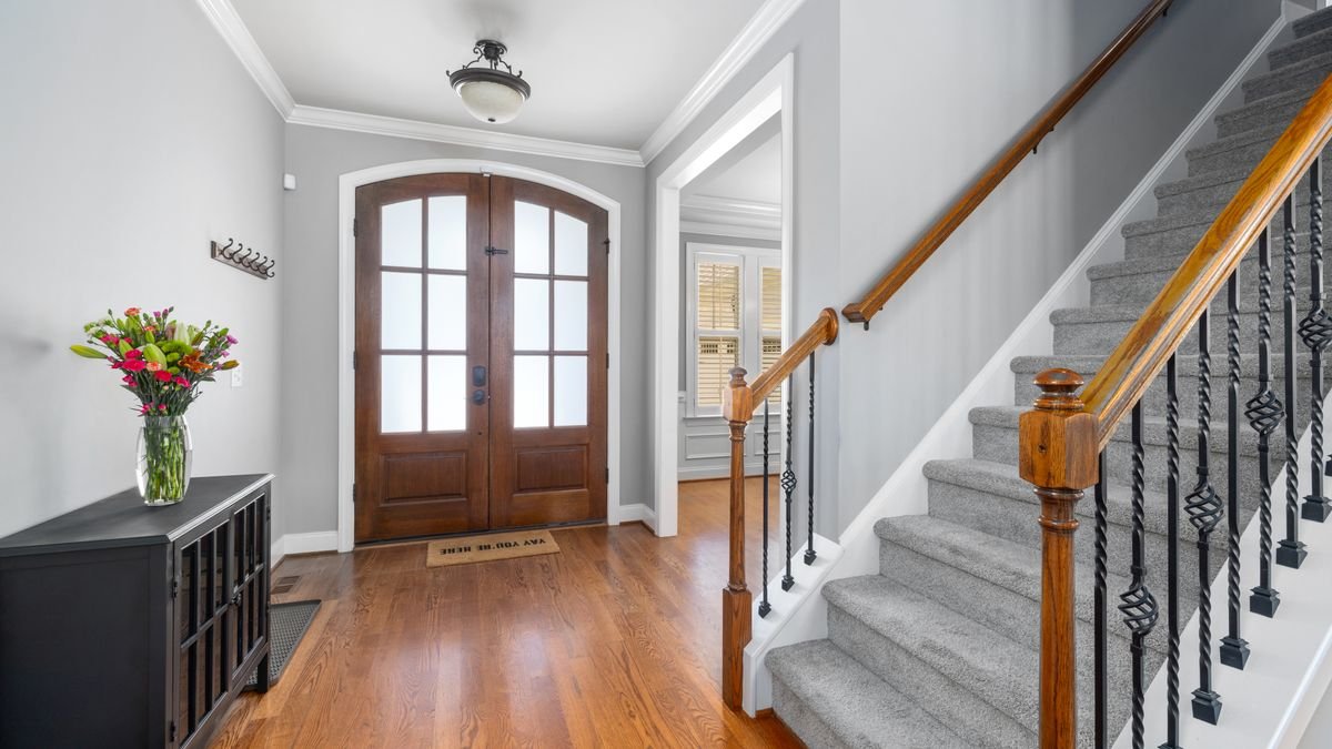 Beautiful home foyer with wooden door, staircase, and decor, perfect for showcasing interior design.