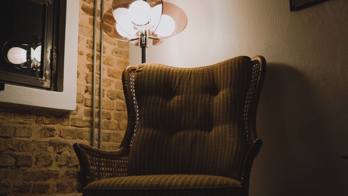 Warm ambient light illuminating an antique chair against a rustic brick wall in Istanbul.