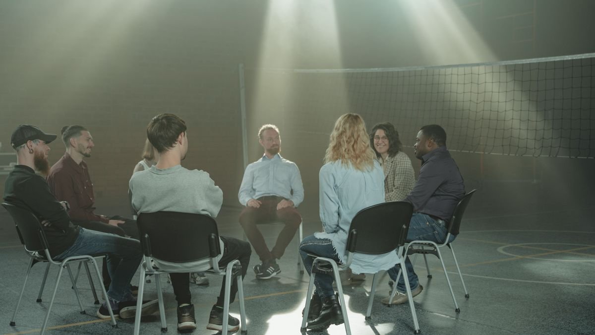 A small group engaging in a therapy session indoors, under rays of sunlight.
