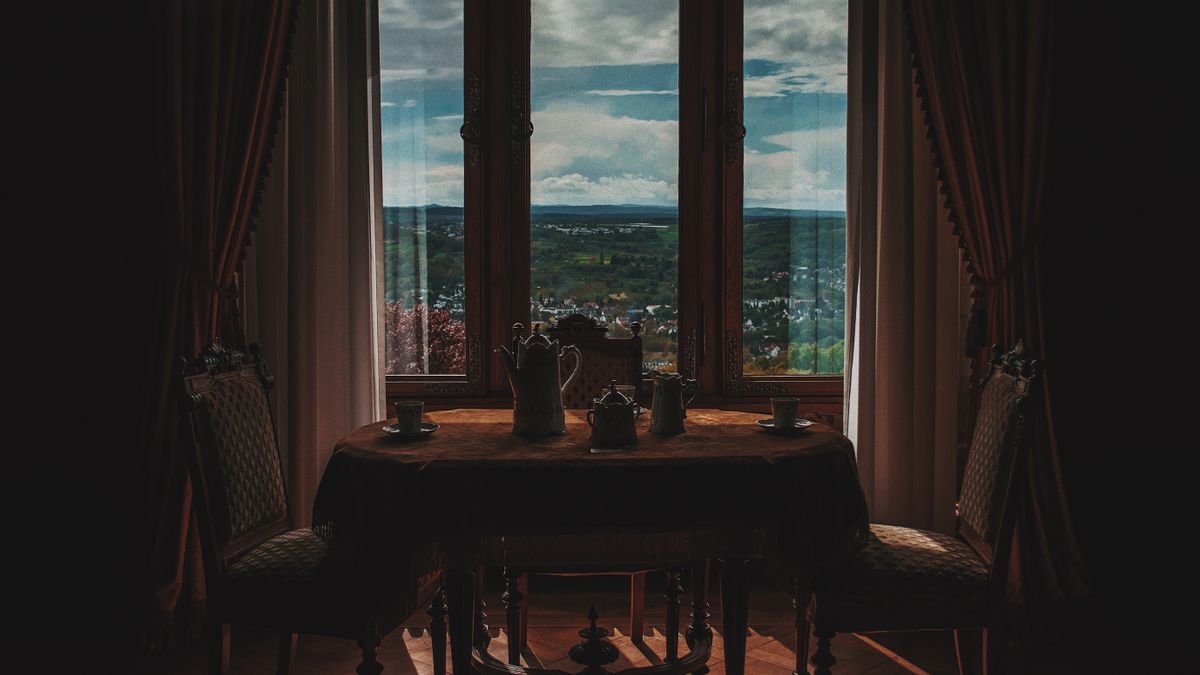 Cozy and elegant dining setup with a view of the countryside through large windows, perfect for relaxation.