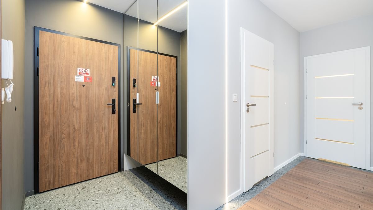 A minimalist hallway with wooden and white doors, showcasing modern interior design.