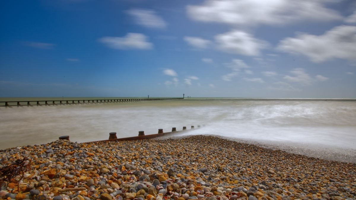 Beautiful coastal landscape of Littlehampton with pebbles and long exposure waves under a clear sky.
