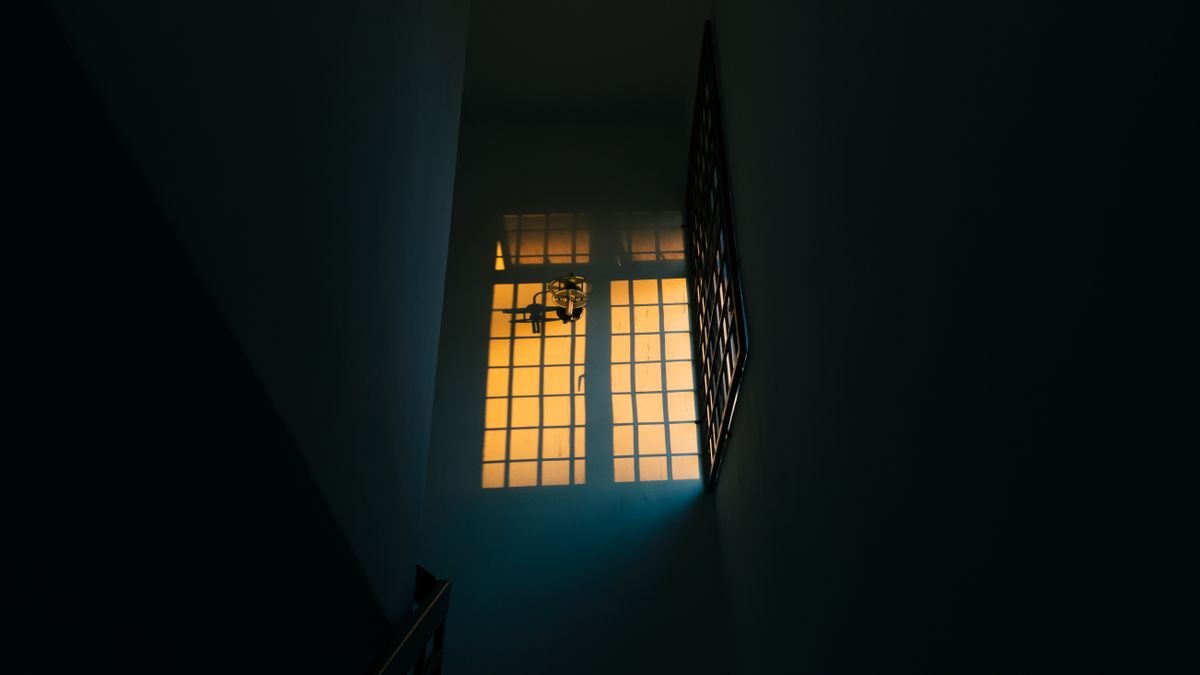 A dimly lit hallway with a warm glow from the window, creating a dramatic contrast.