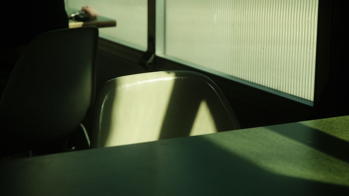Sunlit interior with shadows on chairs and table by a window.