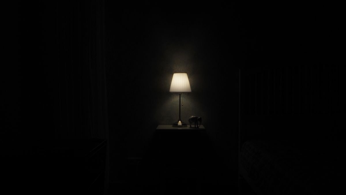 Illuminated lamp on nightstand casting a warm glow in a dark, minimalist room.