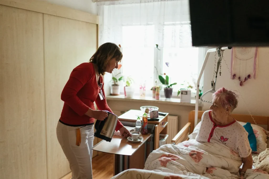 A carer bringing tea to an older woman at home